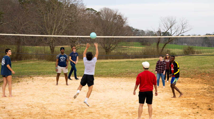 students playing volleyball on sand court