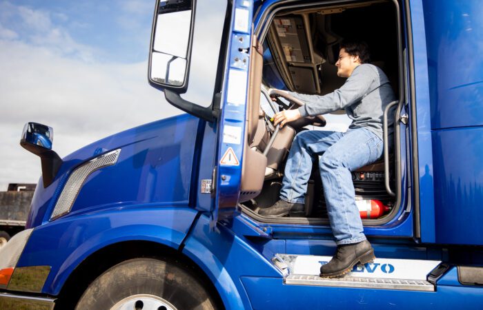 male student in the cab of a blue semi truck